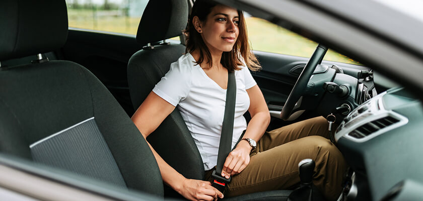 Woman in car putting on her seat belt