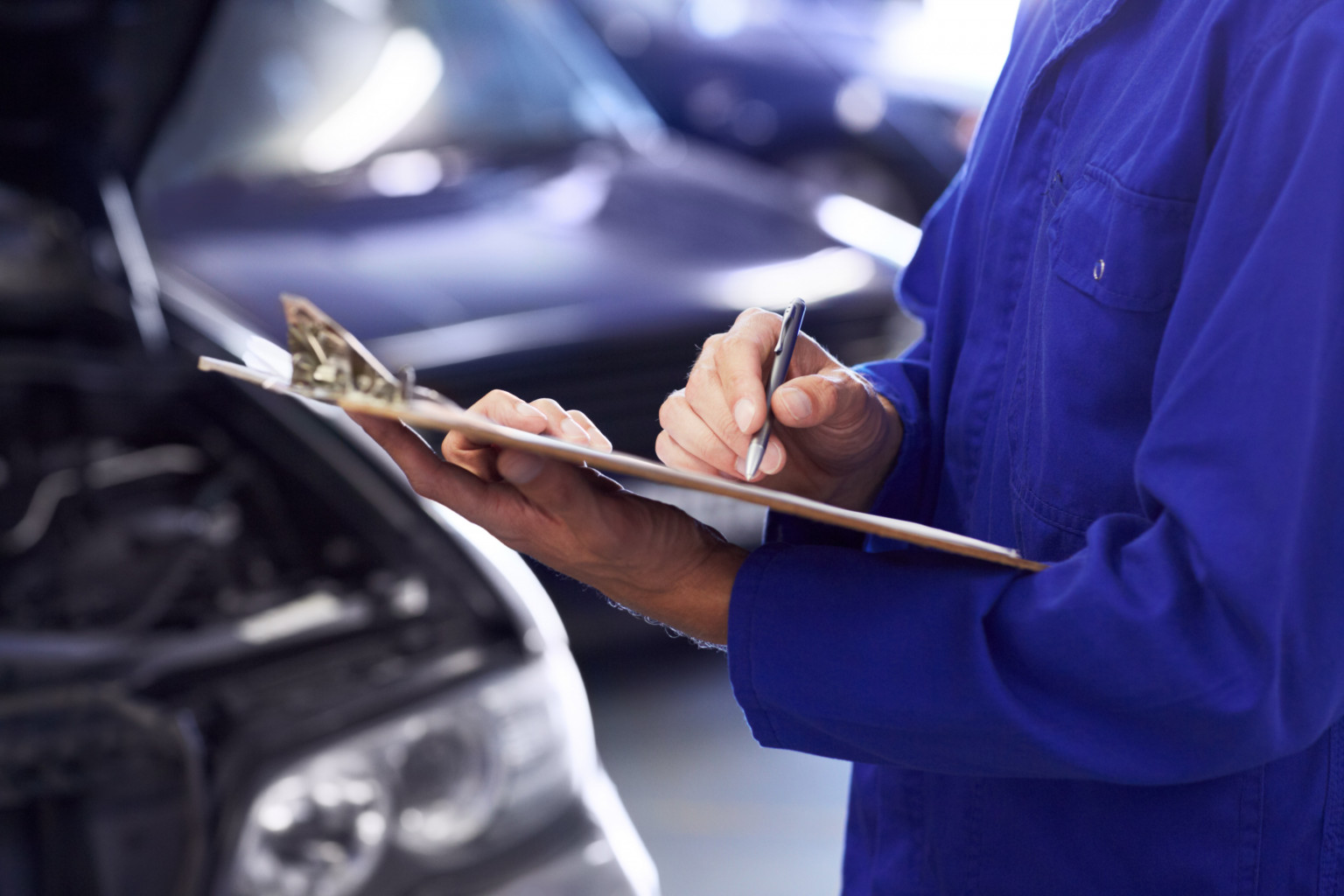 man holding clipboard inspecting car